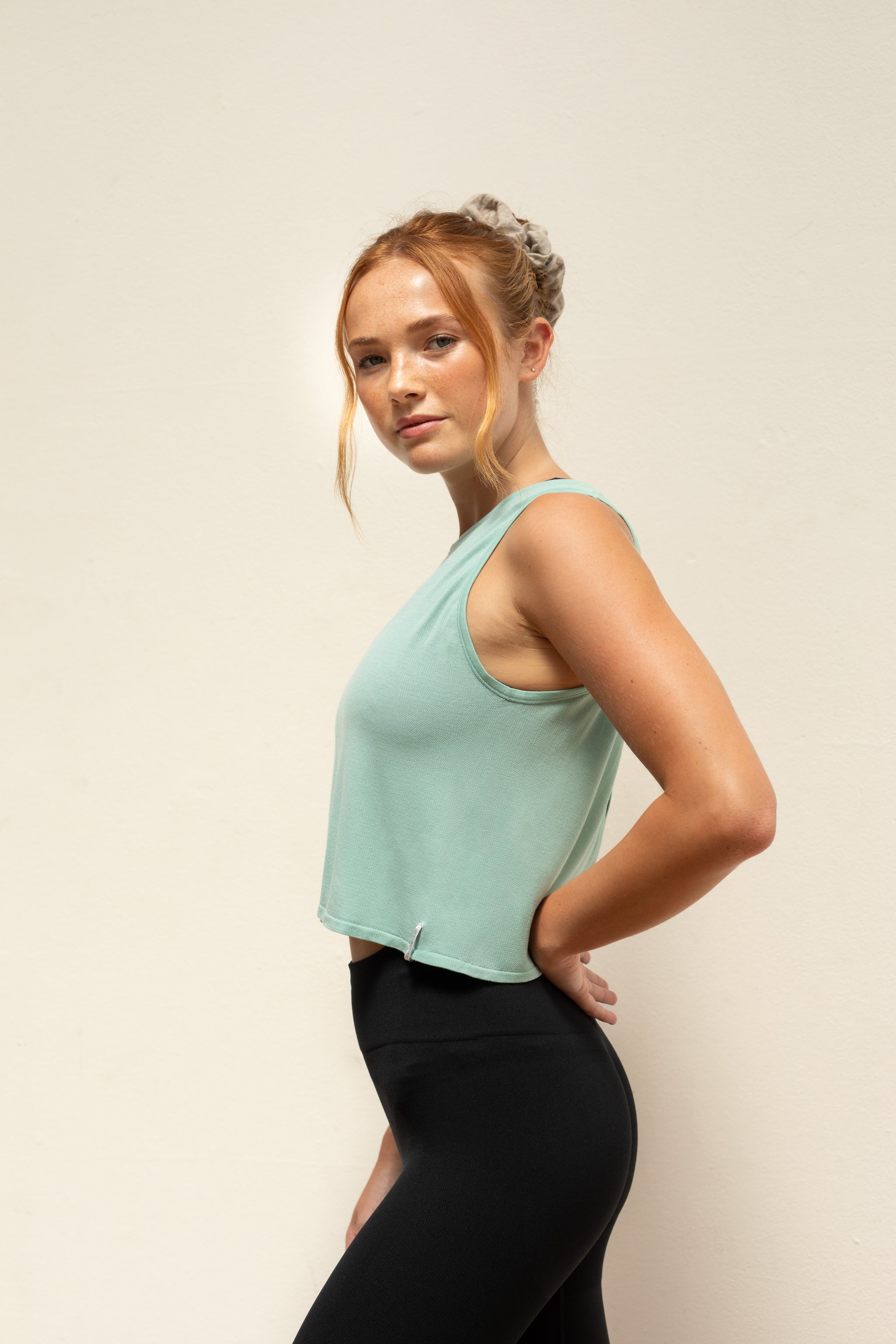 Model wearing black leggings and mint green cropped bamboo top for sustainable activewear brand, Jilla.