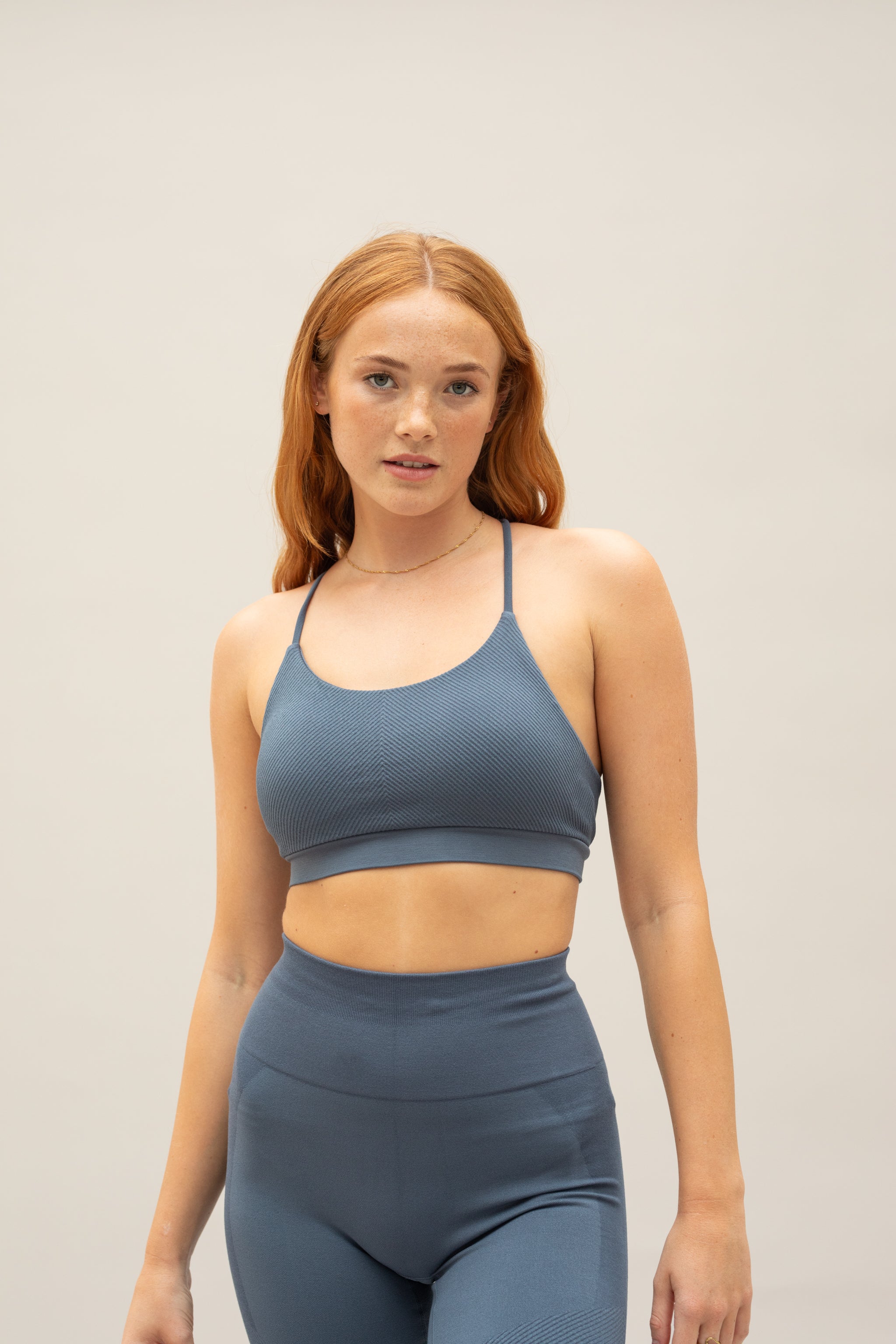 Model wearing blue supportive sports bra and blue cropped leggings for sustainable women activewear brand, Jilla.