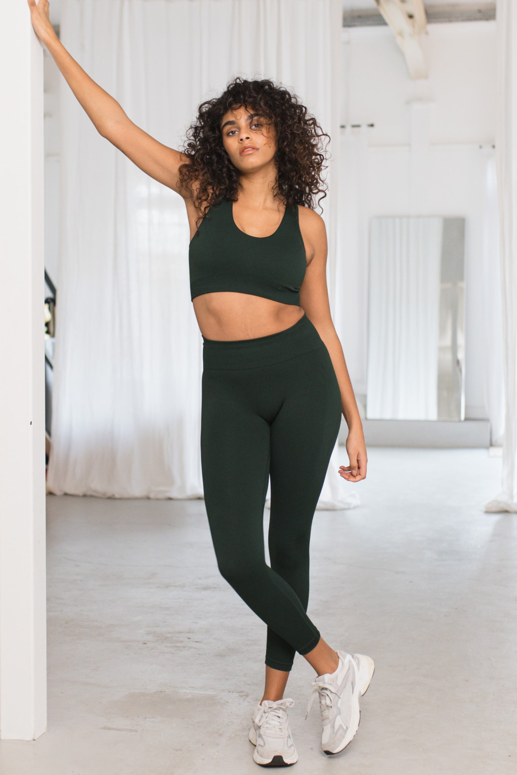 Dark green sculpting, supporting, contouring and shaping 7/8 cropped high waisted leggings with moisture wicking properties for yoga, pilates, barre, gym, running, cycling and exercise by sustainable activewear brand Jilla Active
