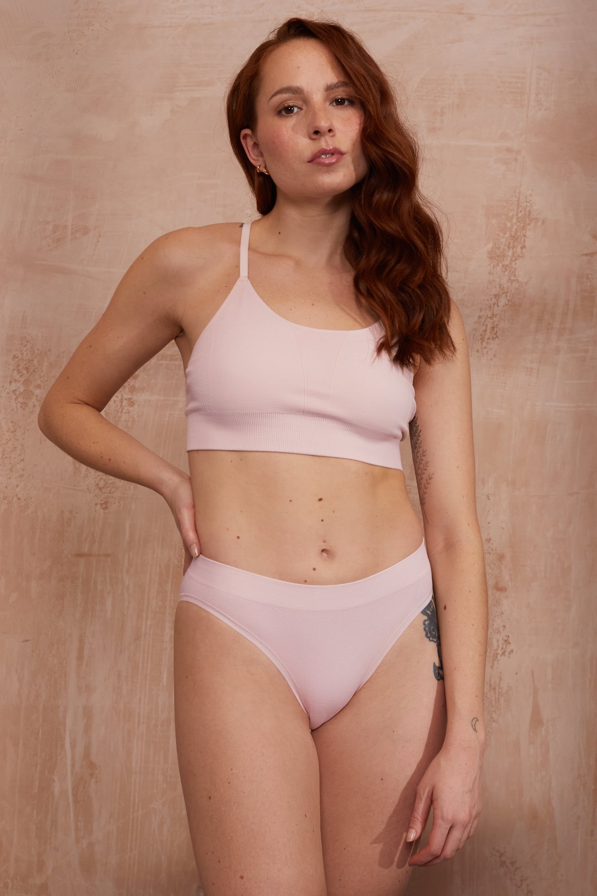 Model wearing pink top and pink thong for sustainable activewear brand, Jilla.