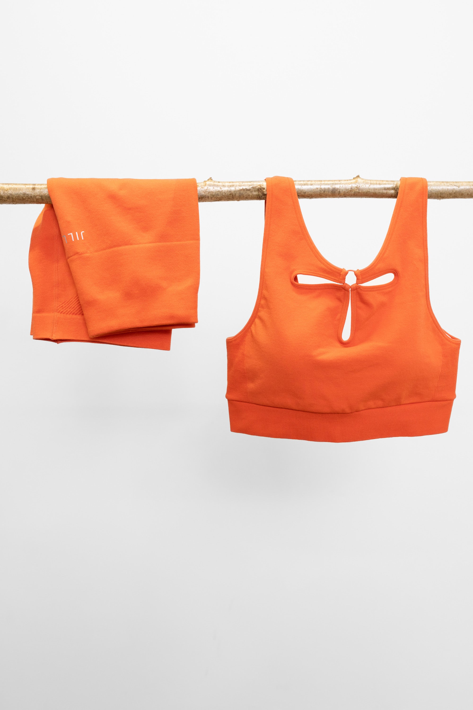 Orange supporting modal sports bra with open back and flower petal front details with orange ribbed sports shorts for pilates, yoga, gym, cycling o exercise by sustainable activewear brand Jilla Active