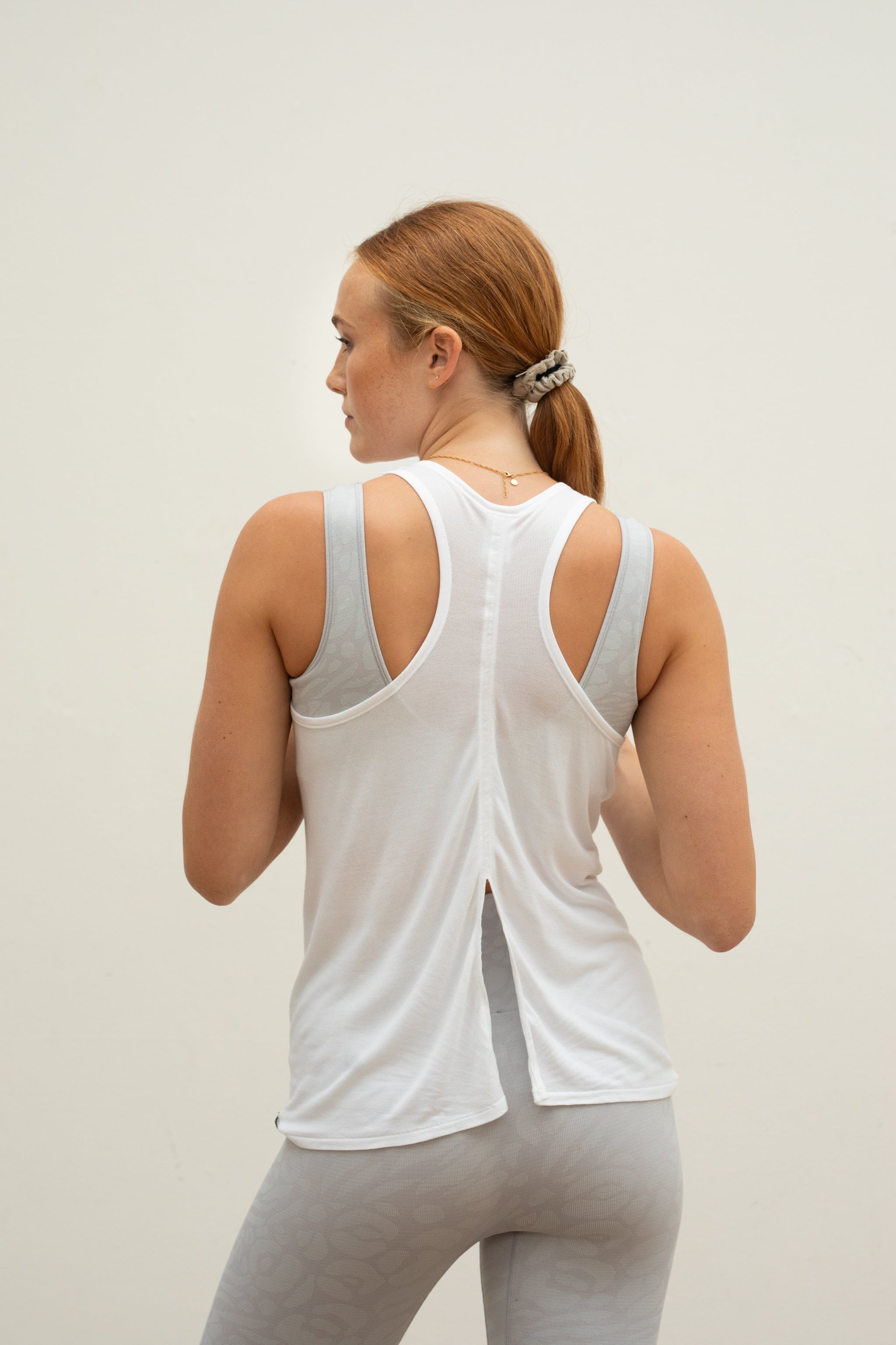 Woman wearing white bamboo tank top for sustainable women's activewear brand Jilla