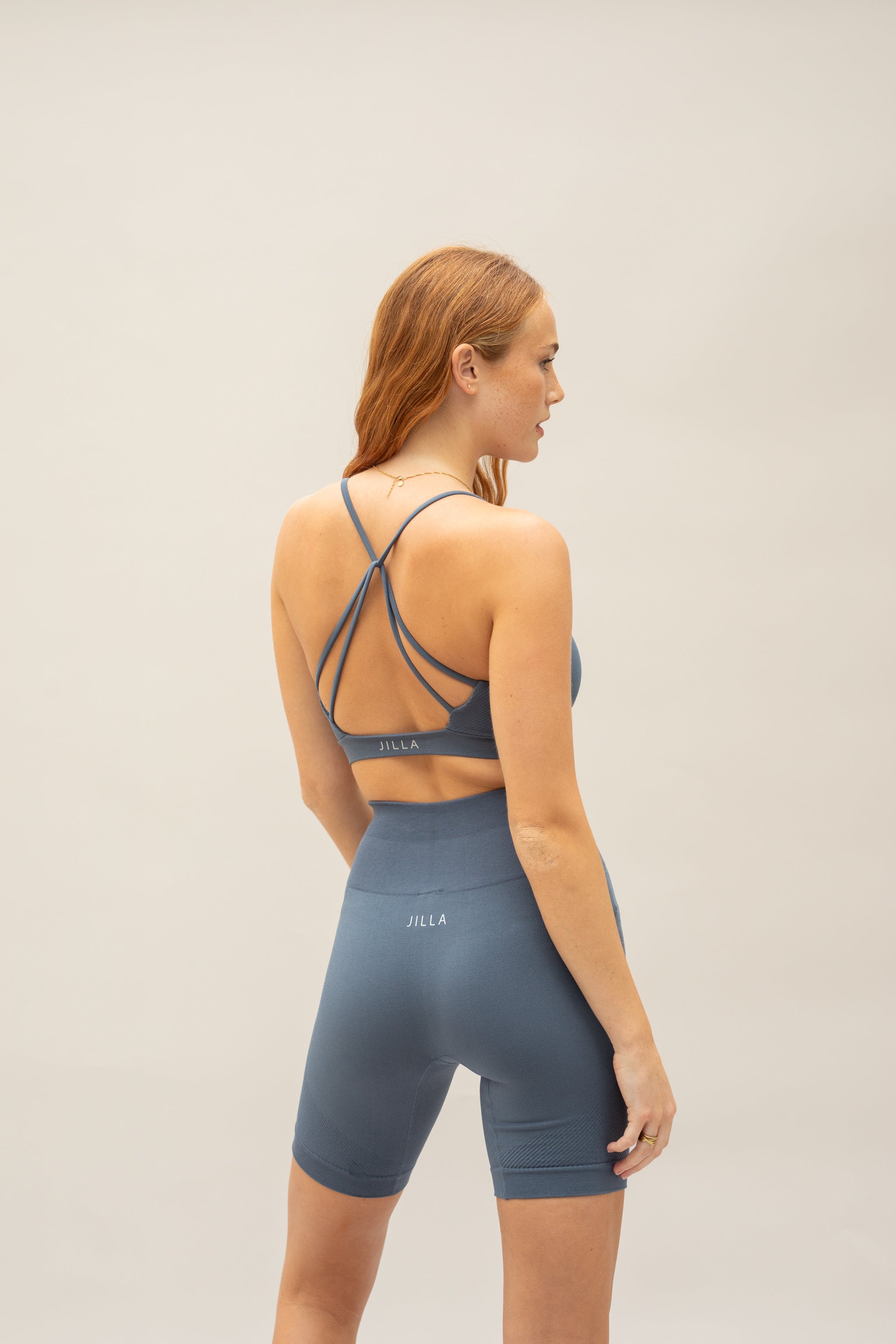 Model wearing steal blue shorts and steal blue supportive sports bra for sustainable activewear brand, Jilla.