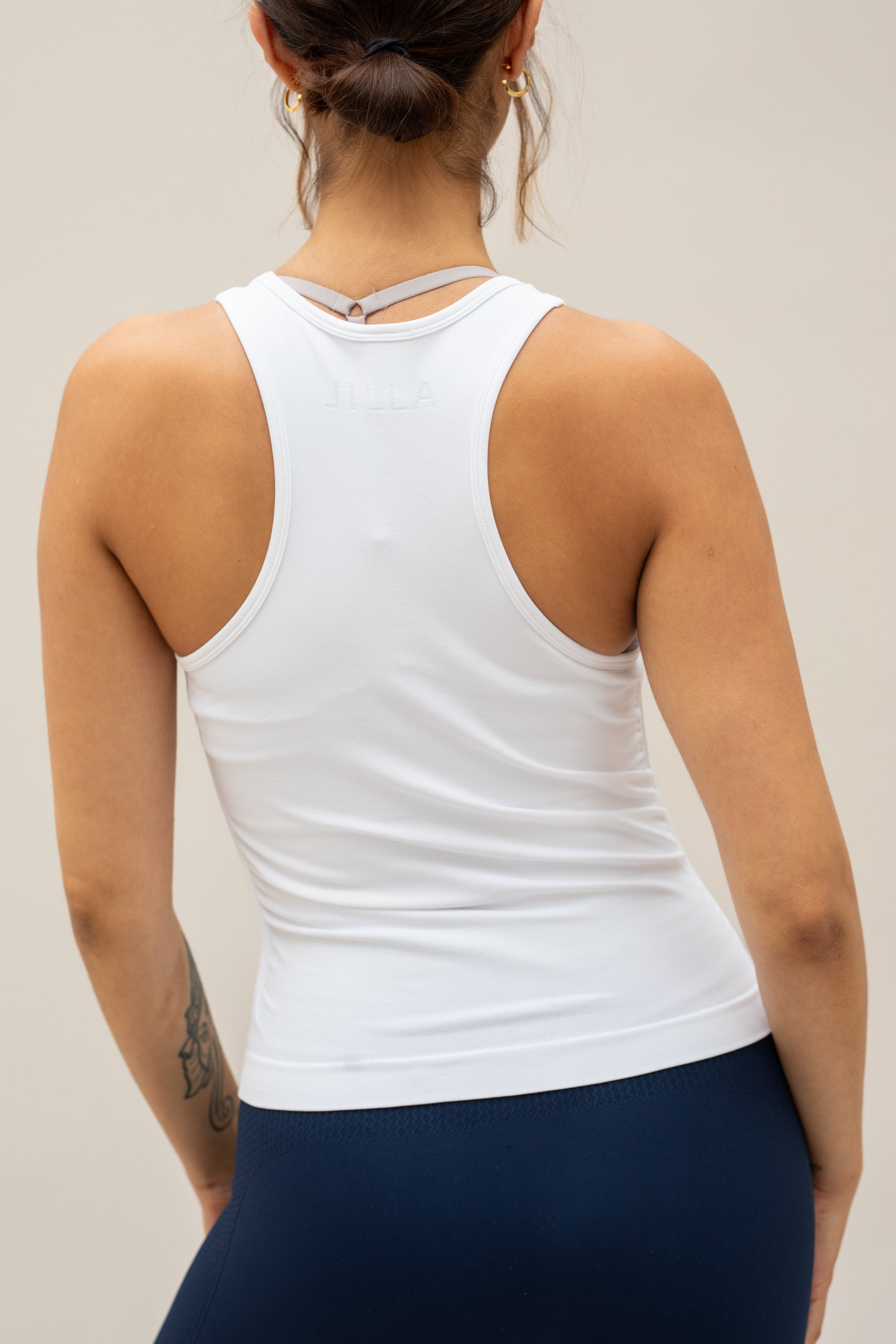 White seamless recycled moisture wicking sleeveless tank top with side ruching for yoga, pilates, gym, cycling, running and exercise by sustainable activewear brand Jilla Active