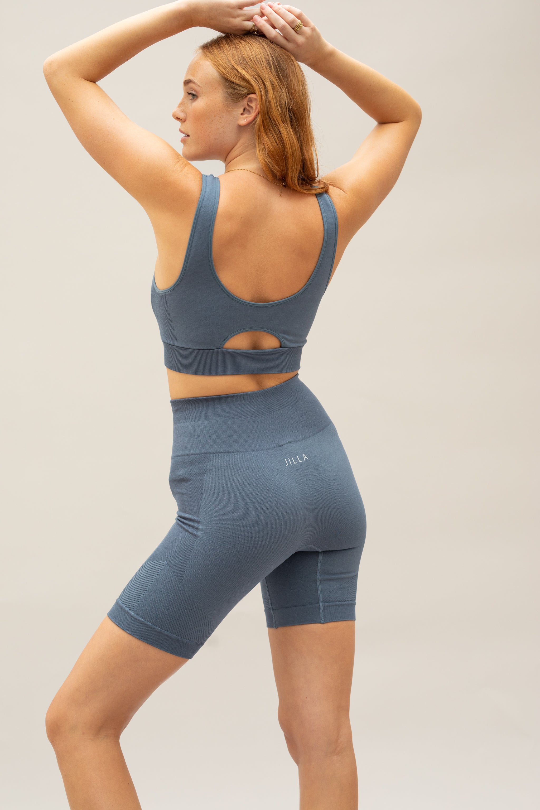 Model wearing blue supportive sports bra and blue yoga shorts for sustainable activewear brand Jilla