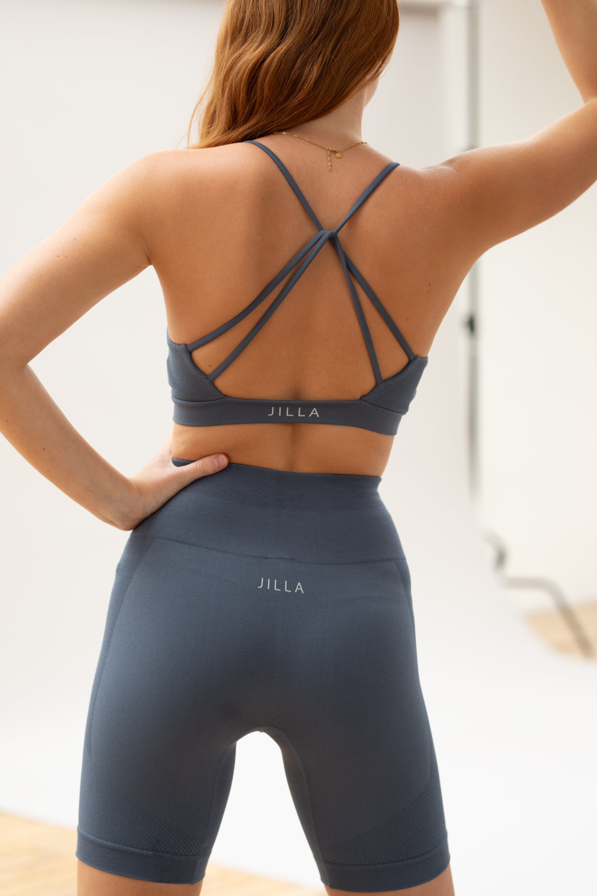 Model wearing blue supportive sports bra and blue cropped leggings for sustainable women activewear brand, Jilla.