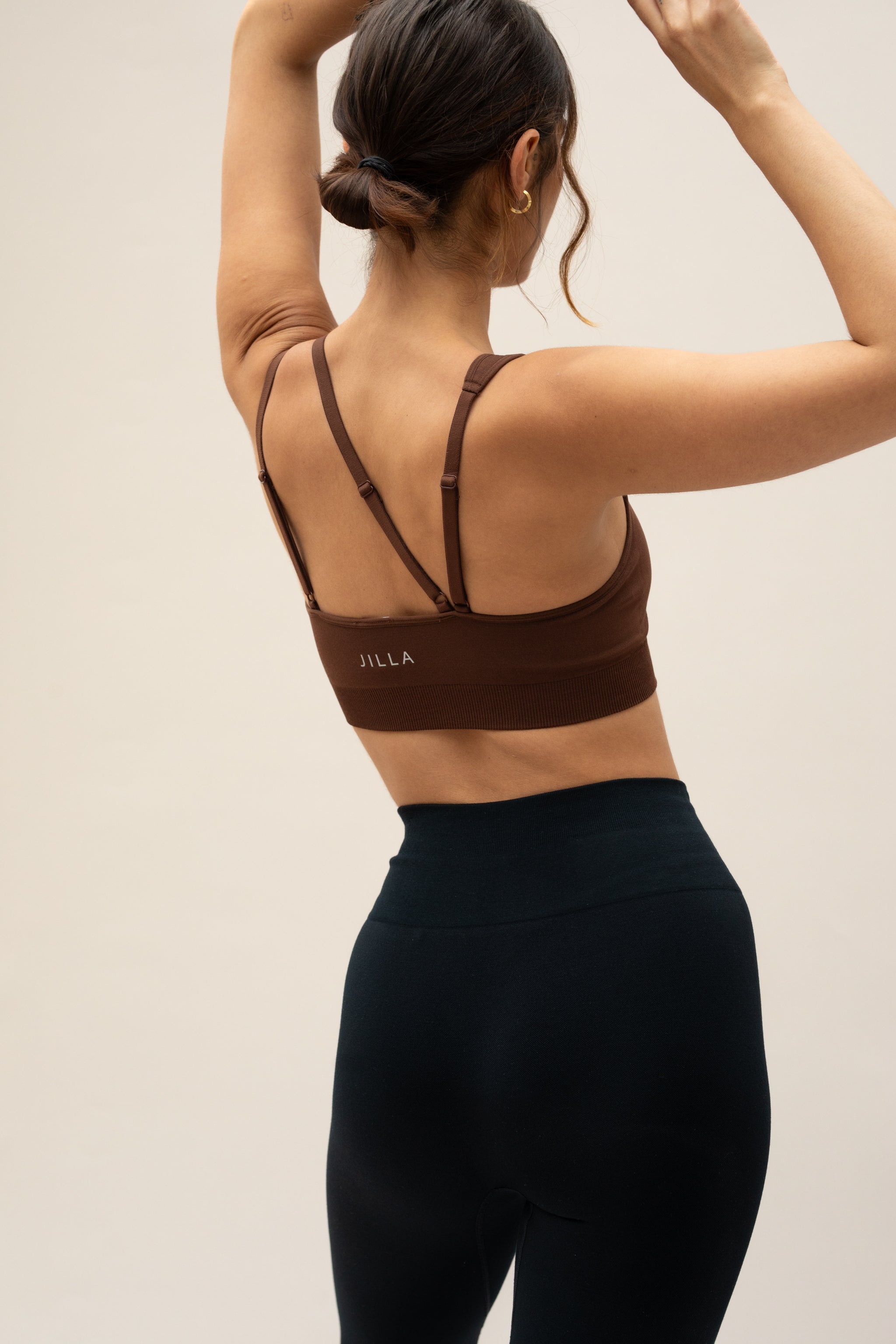 Model wearing brown shorts and supportive sports bra for sustainable activewear brand, Jilla.