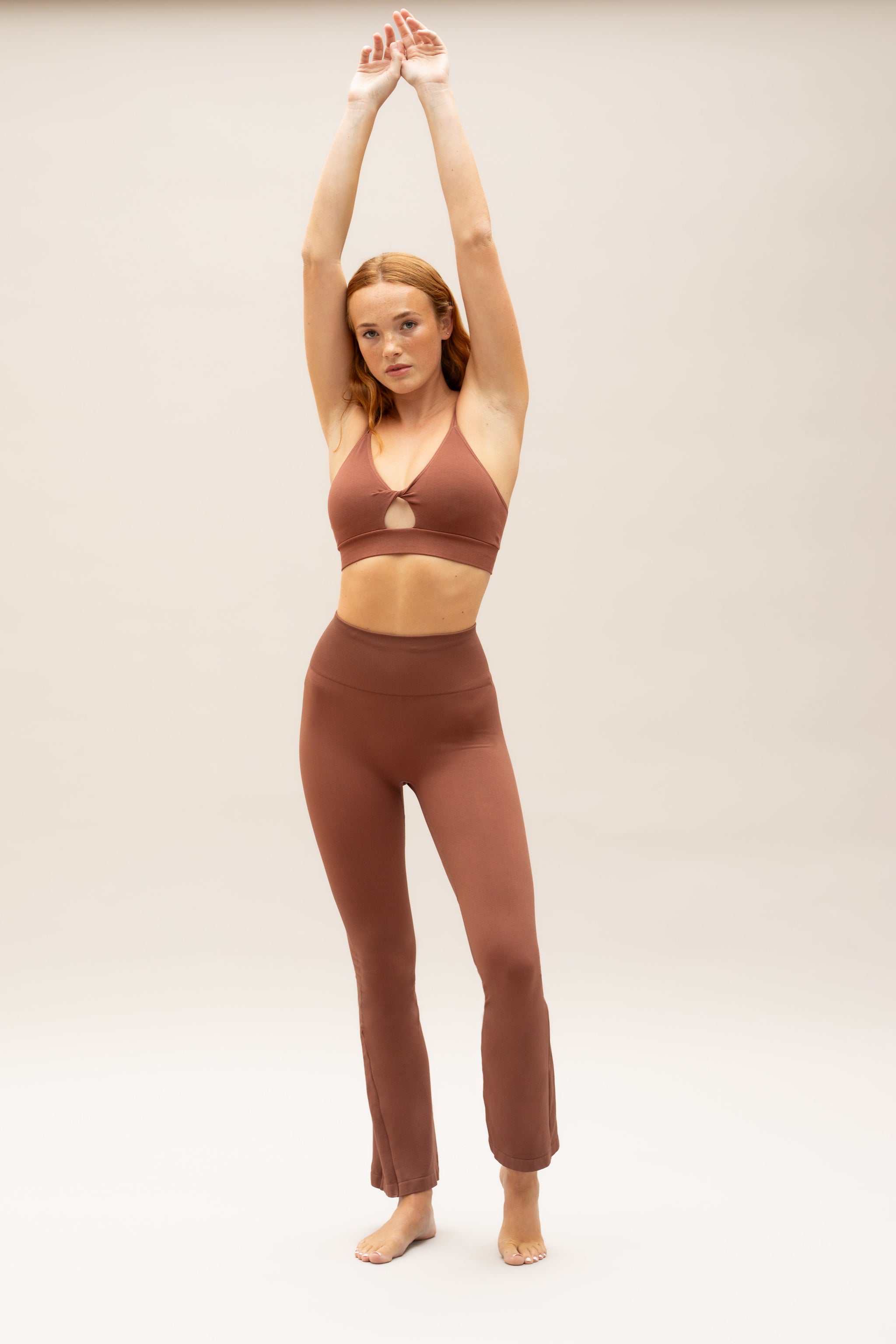 Brown supportive twisted from sports bra and brown high waisted flare leggings from sustainable activewear brand, Jilla.
