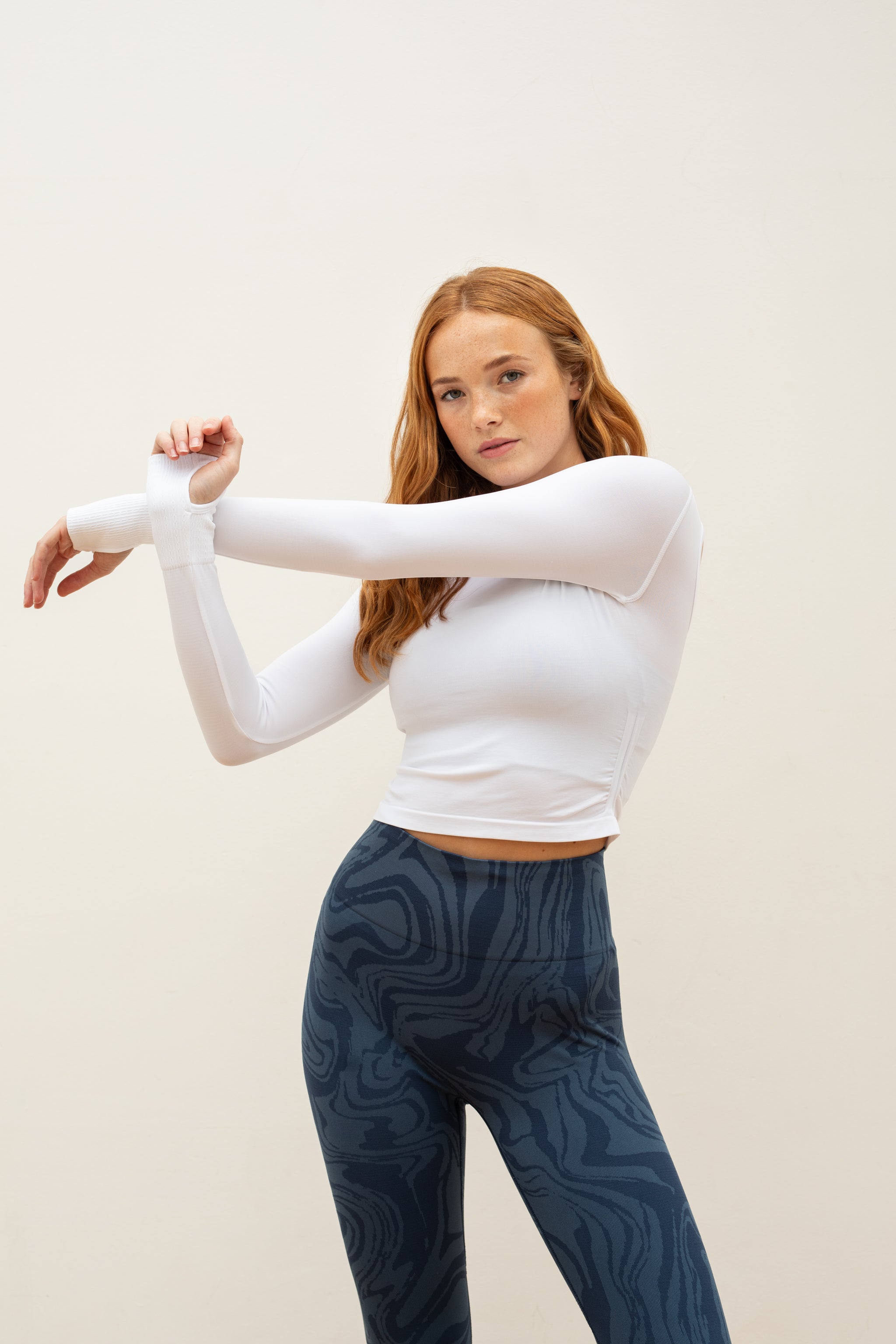 White long sleeve recycled crop top with blue leggings from sustainable women's activewear brand, Jilla. 