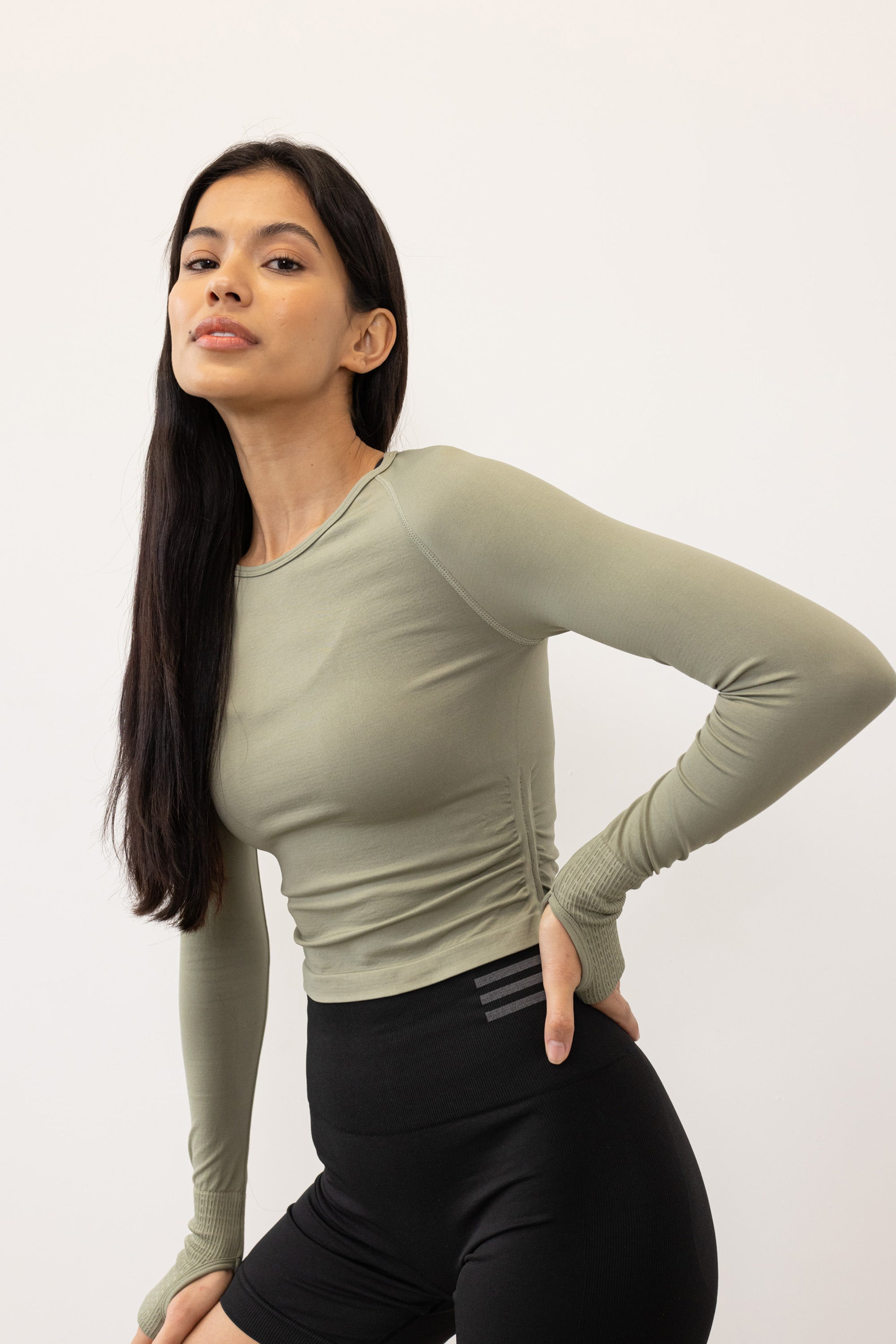 Seagrass green cutout back cropped long sleeve top with thumbholes and side ruching made from recycled fabrics for yoga, pilates, cycling, gym and exercise by sustainable activewear brand Jilla Active