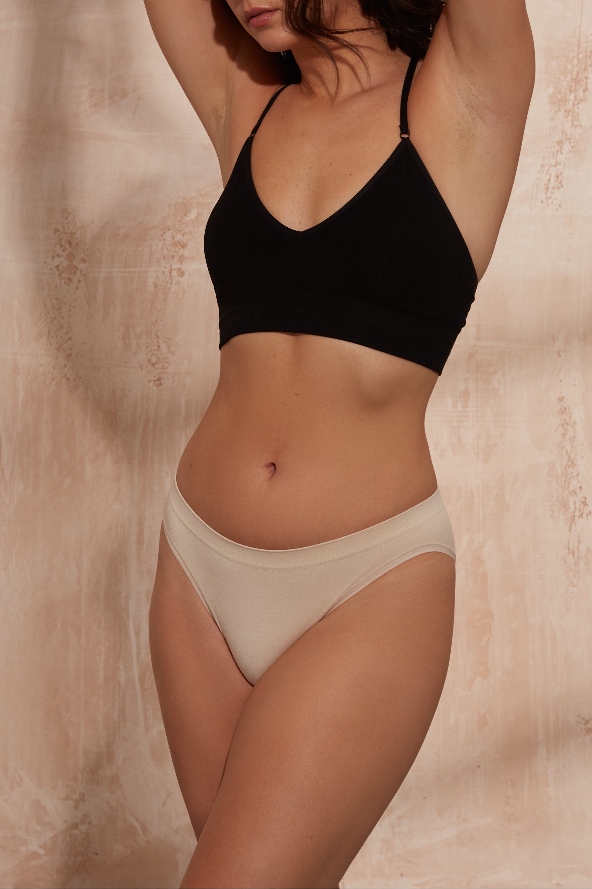 Model wearing black top and beige briefs for sustainable activewear brand, Jilla.
