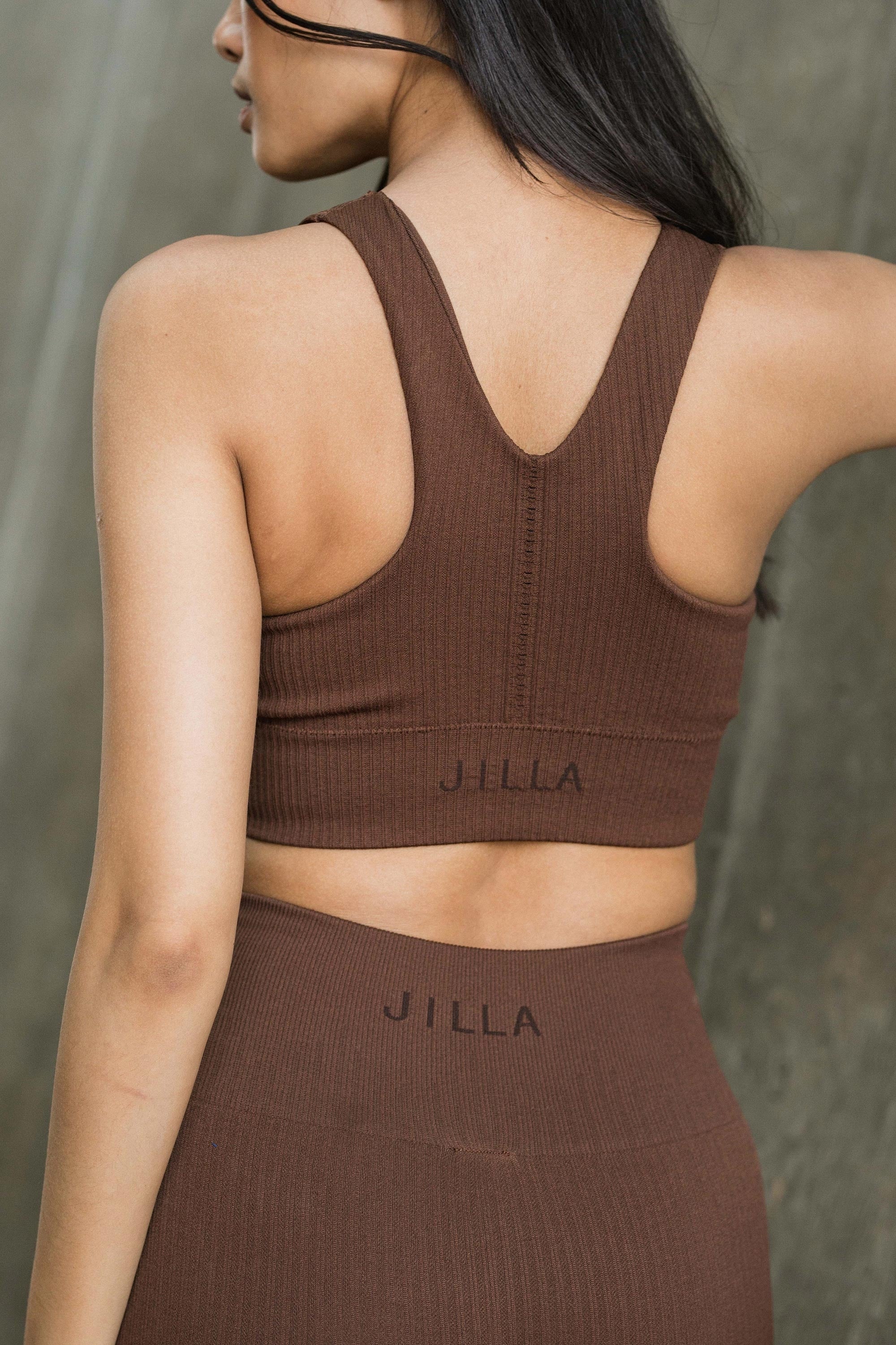 model wearing brown recycled sports bra and brown leggings for sustainable women activewear brand, Jilla. 