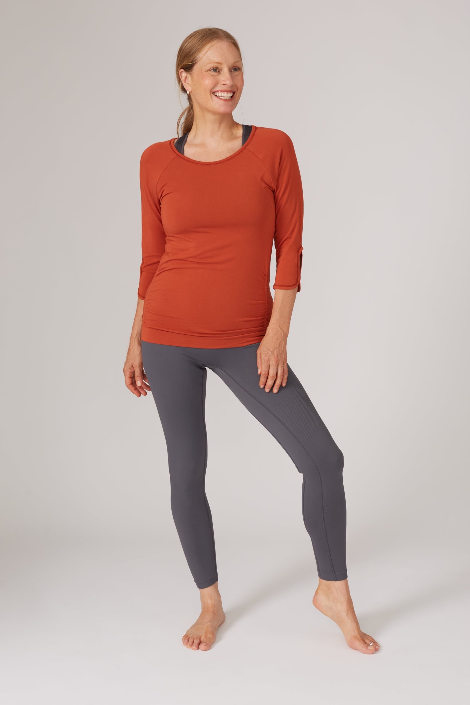 Bright burnt orange bamboo long sleeve top and dark grey leggings for yoga, pilates, barre and running from sustainable activewear brand, Jilla Active