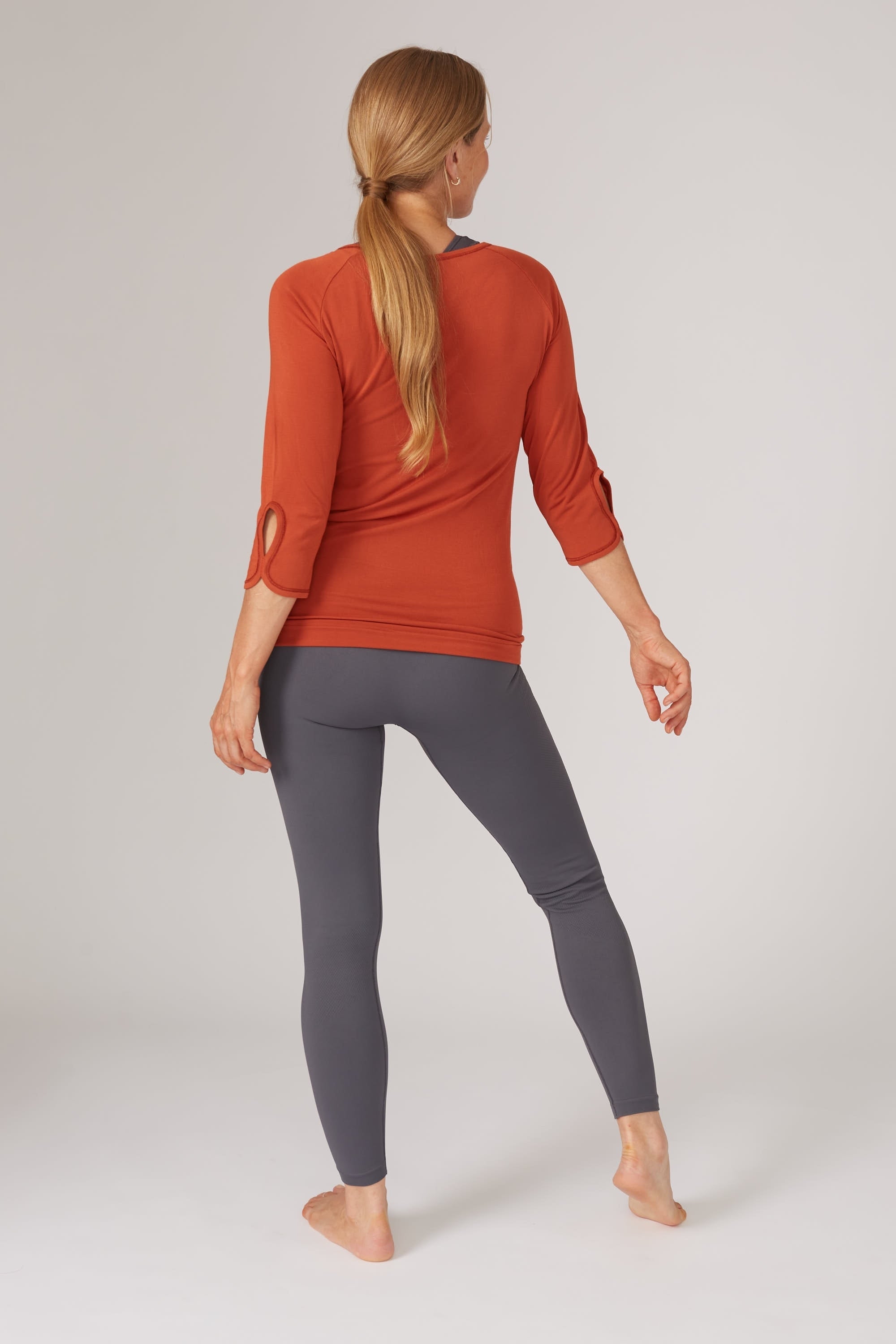 Bright burnt orange bamboo long sleeve top and dark grey leggings for yoga, pilates, barre and running from sustainable activewear brand, Jilla Active