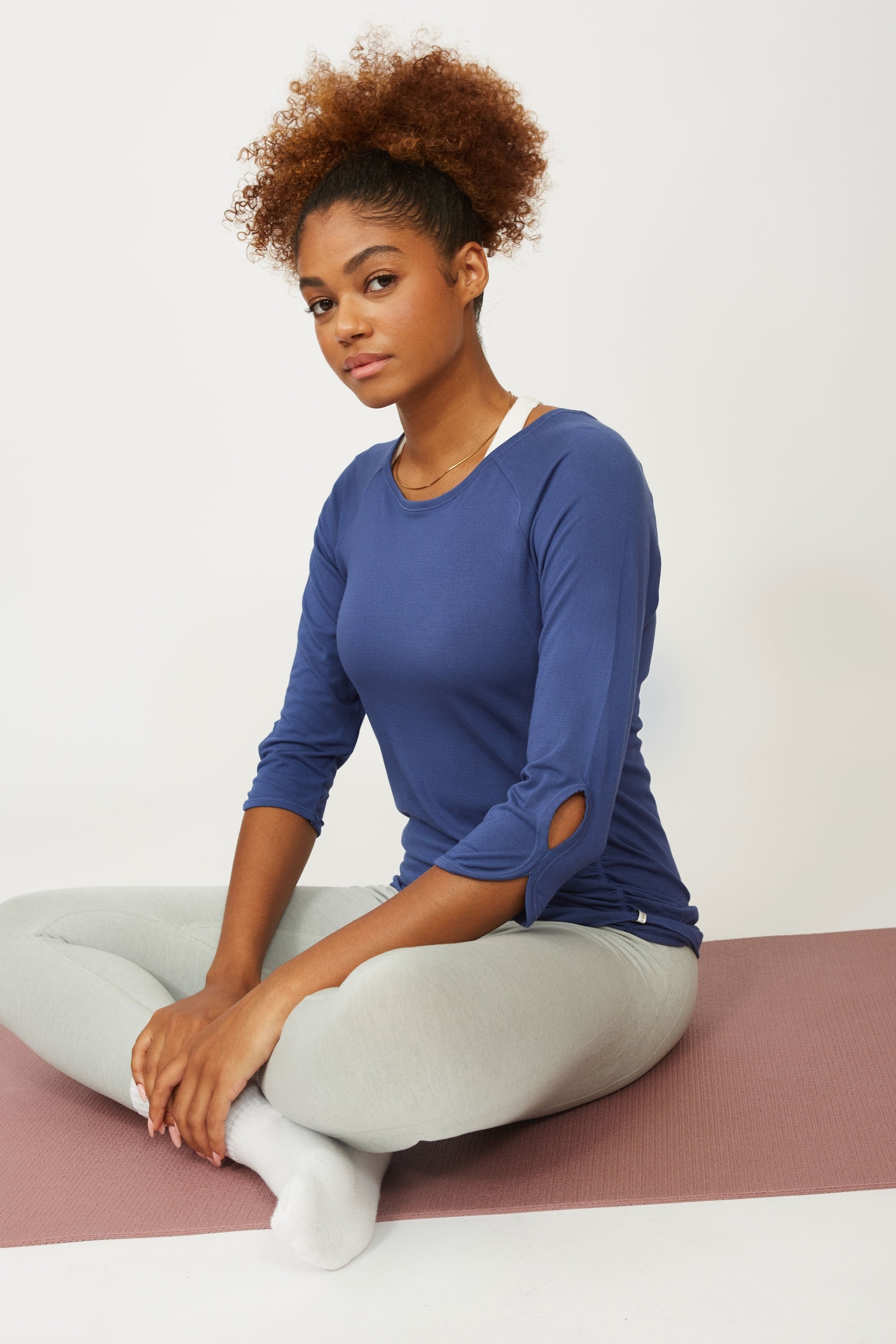 Model wearing blue long sleeve top and grey leggings for sustainable activewear brand, Jilla.