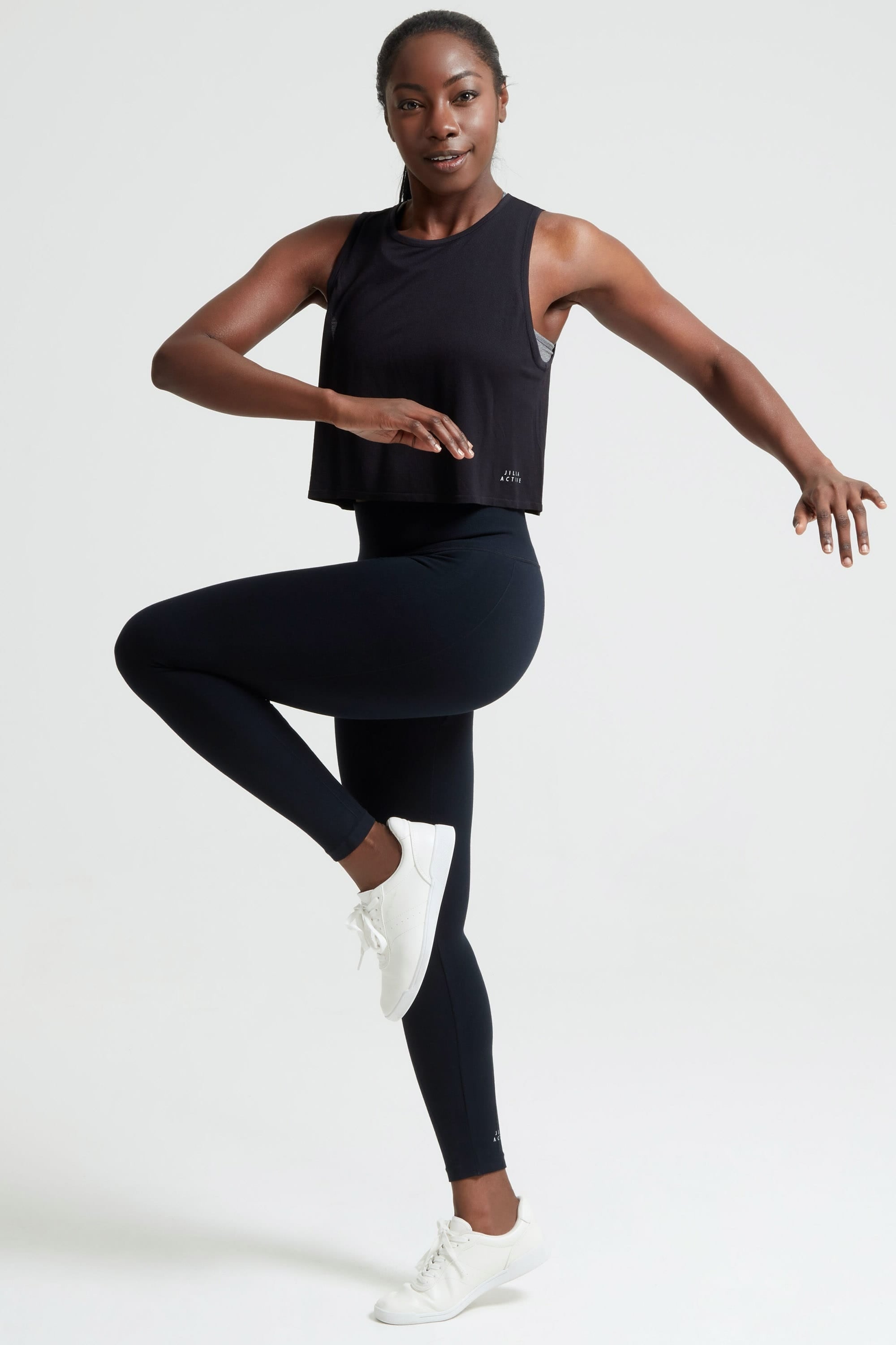 Model wearing black leggings and black sports yoga top for sustainable activewear brand, Jilla.  