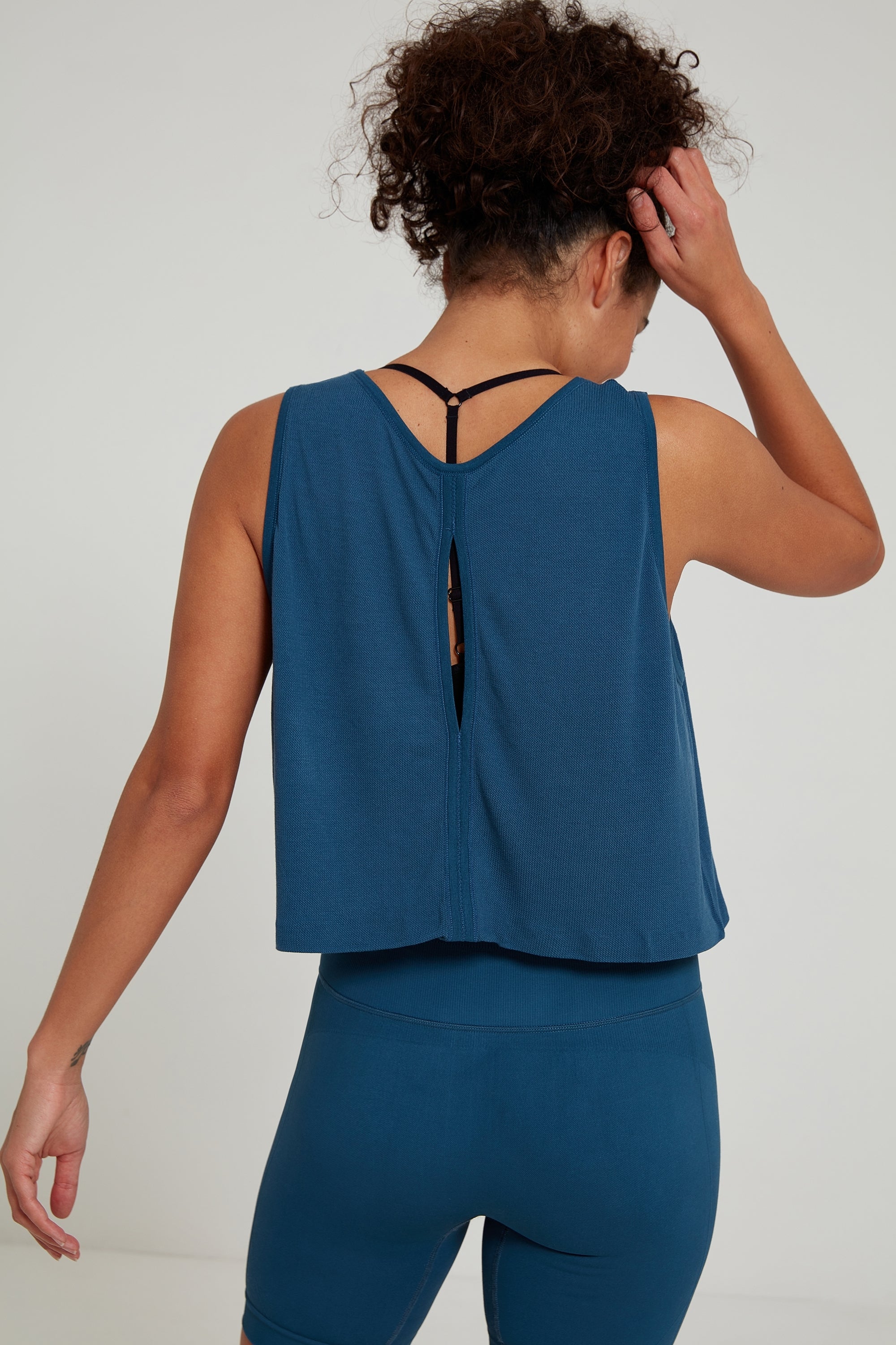 Model wearing blue leggings and blue sports yoga tank top for sustainable activewear brand, Jilla.  