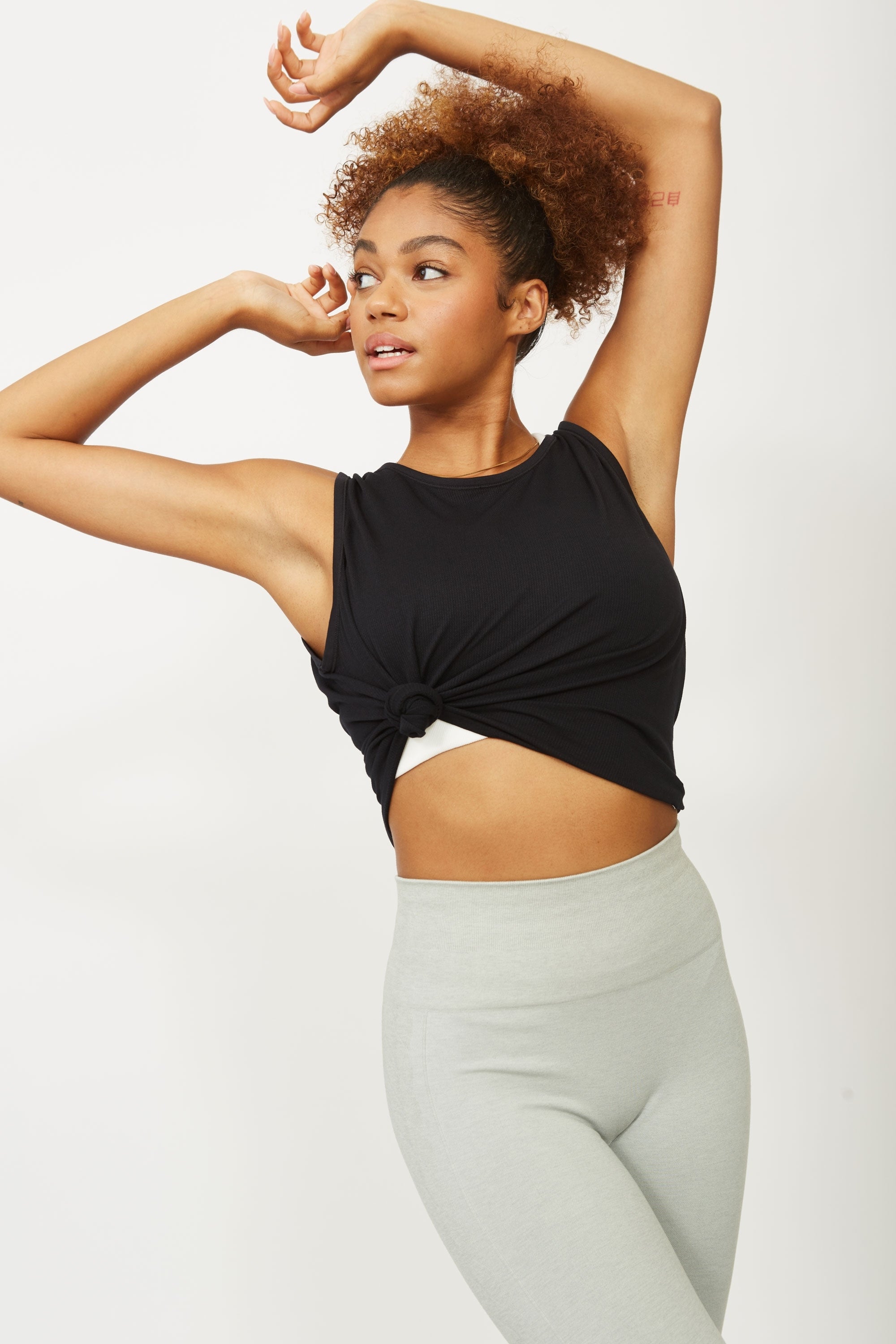 Model wearing grey leggings and black sports yoga top for sustainable activewear brand, Jilla.  