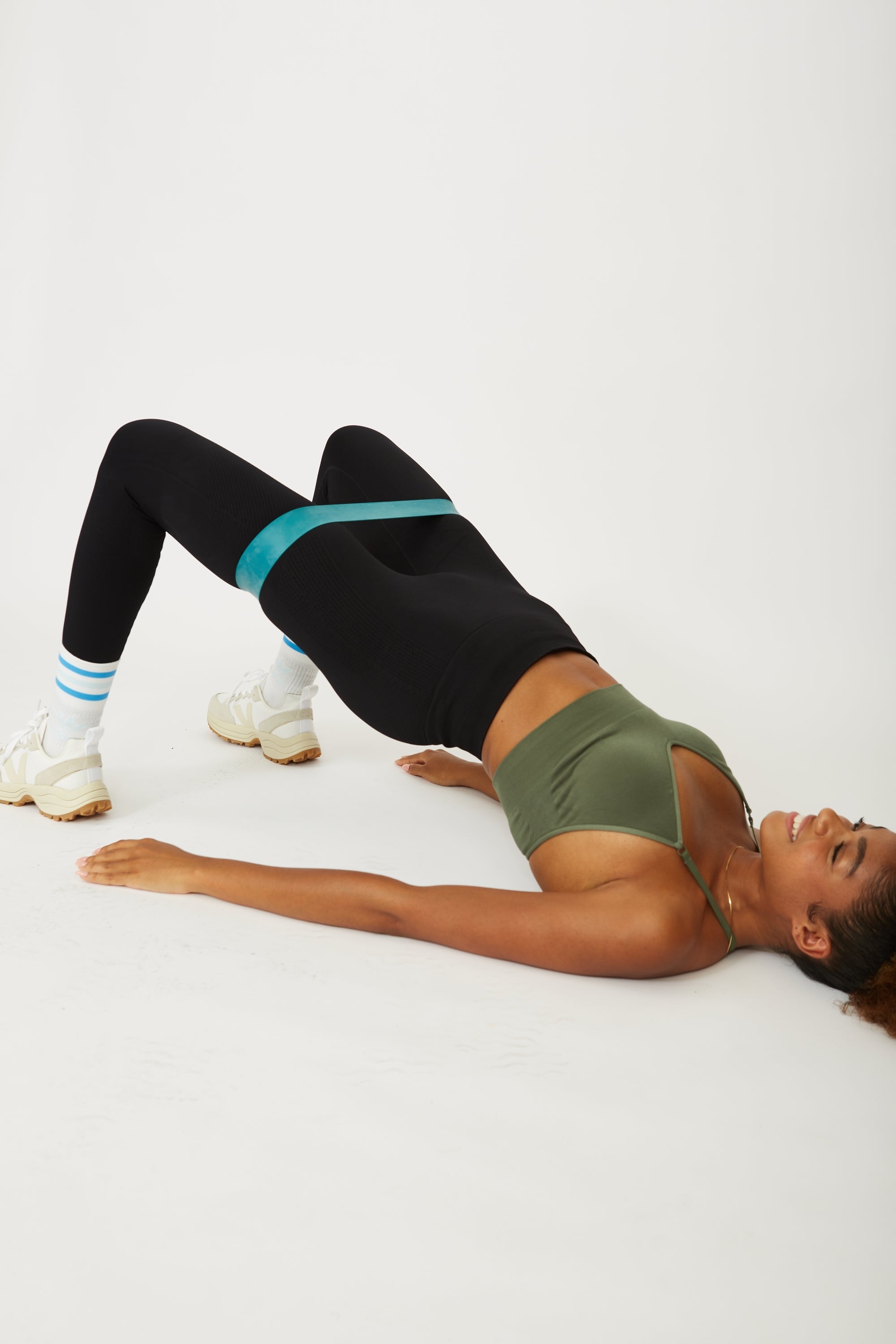 Model wearing black leggings and green supportive sports bra for sustainable activewear brand, Jilla.