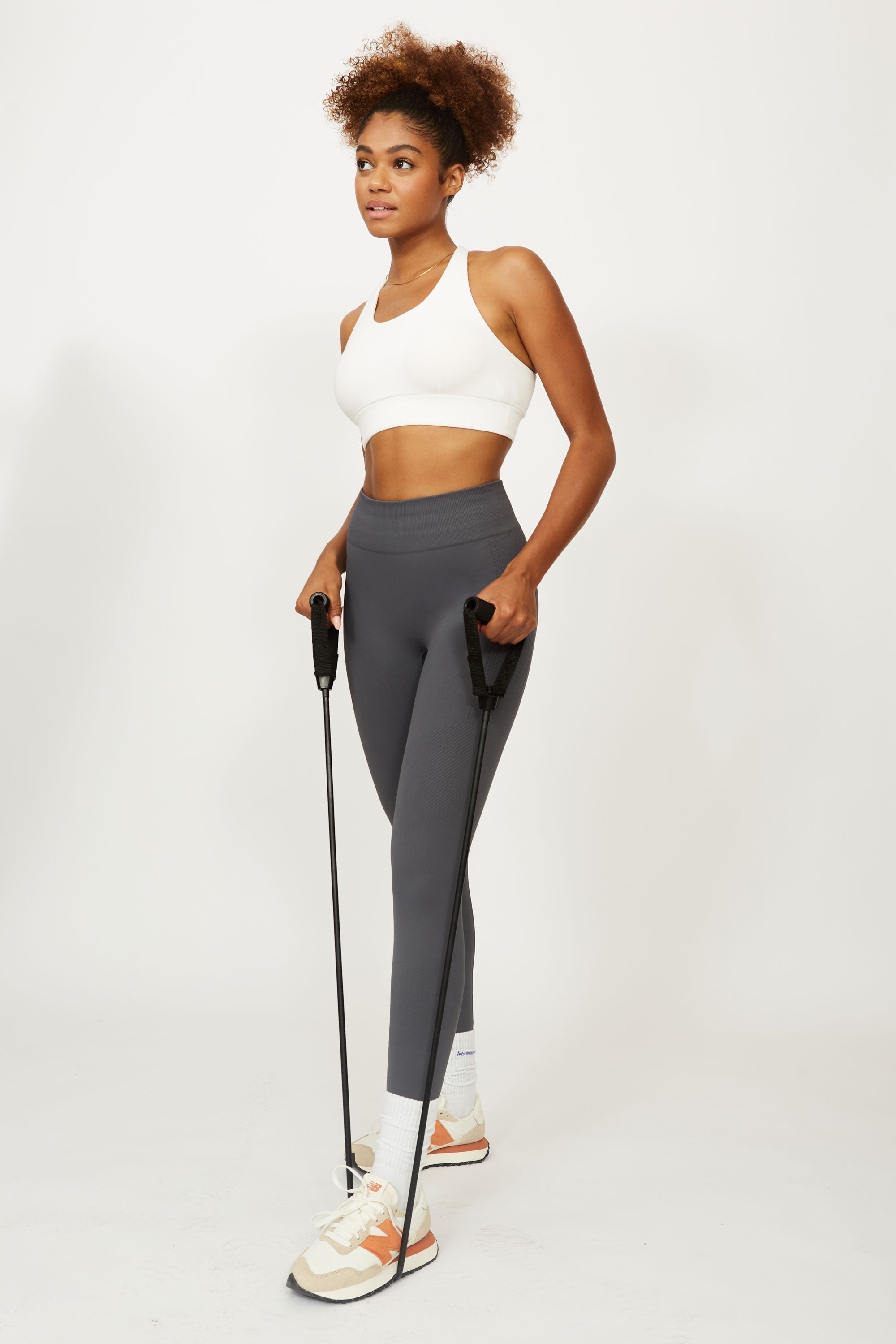 Model wearing grey leggings and white supportive sports bra for sustainable activewear brand, Jilla.