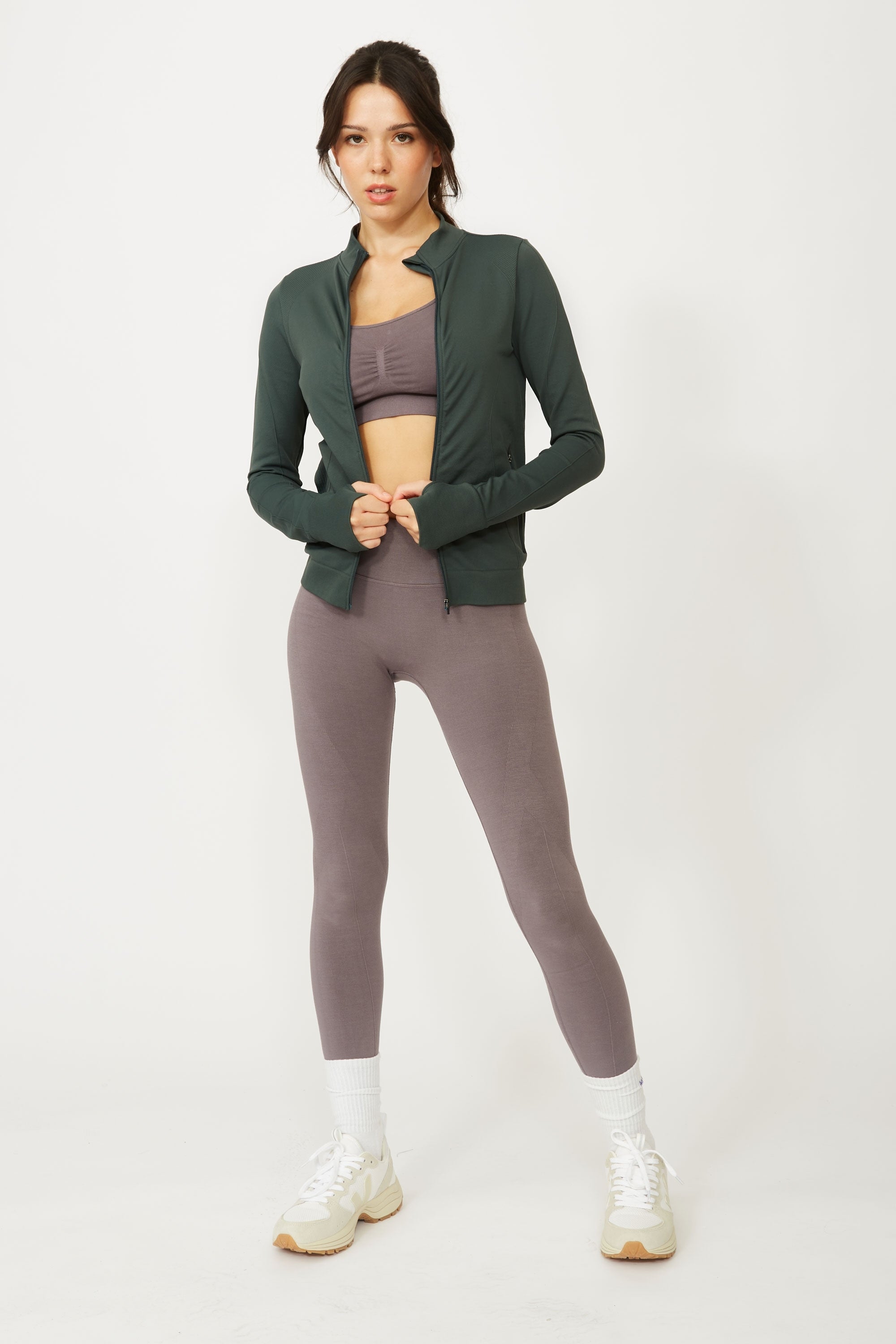Model wearing green jacket over beige activewear set for sustainable yoga brand, Jilla