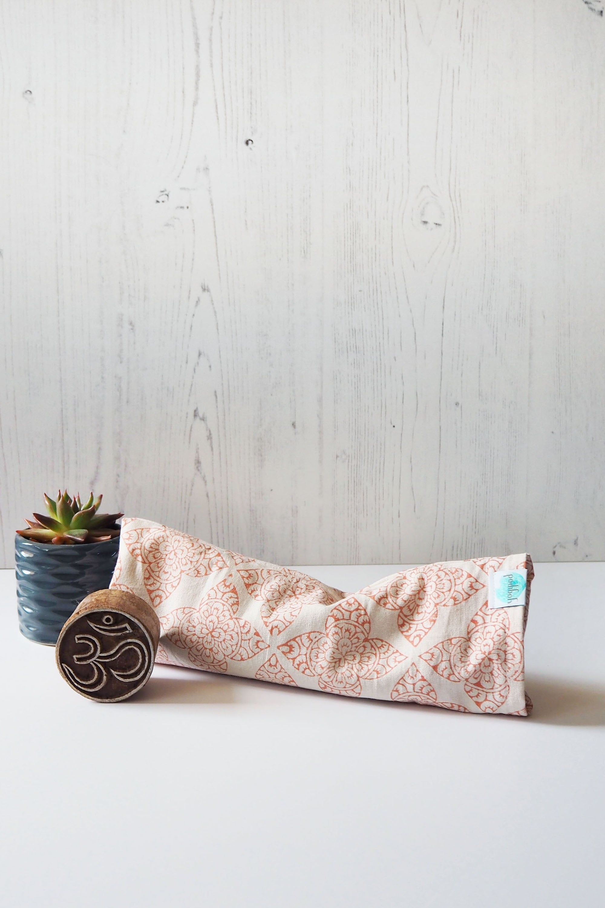 Handcrafted eye pillow from Yogi Pod, designed to enhance relaxation. Created in the UK with hand block printed cotton from Rajasthan. Linseed-filled and customizable with calming oils. Versatile for yoga or as decorative and functional home accessories."